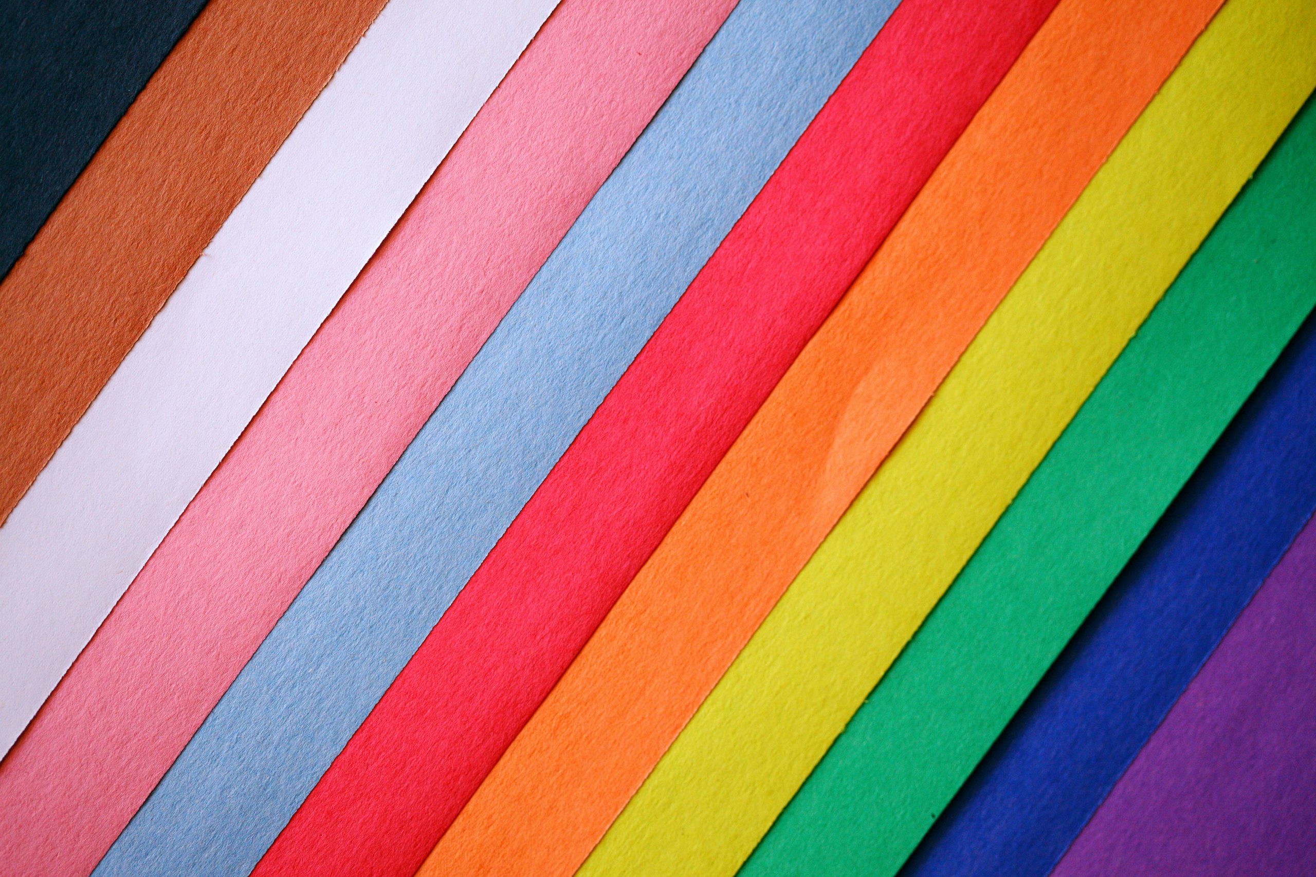 Colorful diagonal arrangement of textured papers creating a vibrant rainbow pattern.